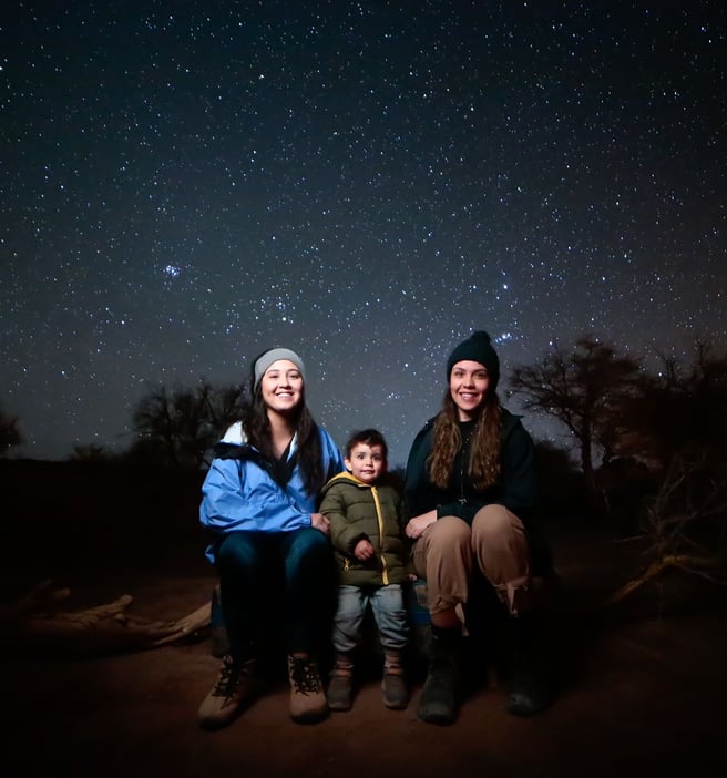 Familia bajo las estrellas con ropa ligera y cálida